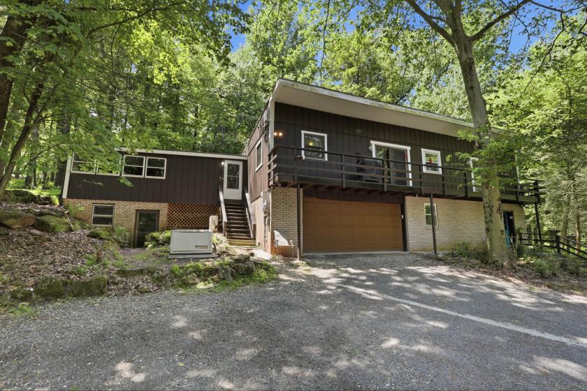 Front exterior with elevated deck and two-car garage at 7 Conewago Hills Rd, Mount Gretna PA